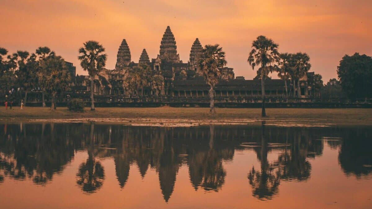 Tranquil sunrise view of Angkor Wat reflecting in calm lake waters, Siem Reap, Cambodia.