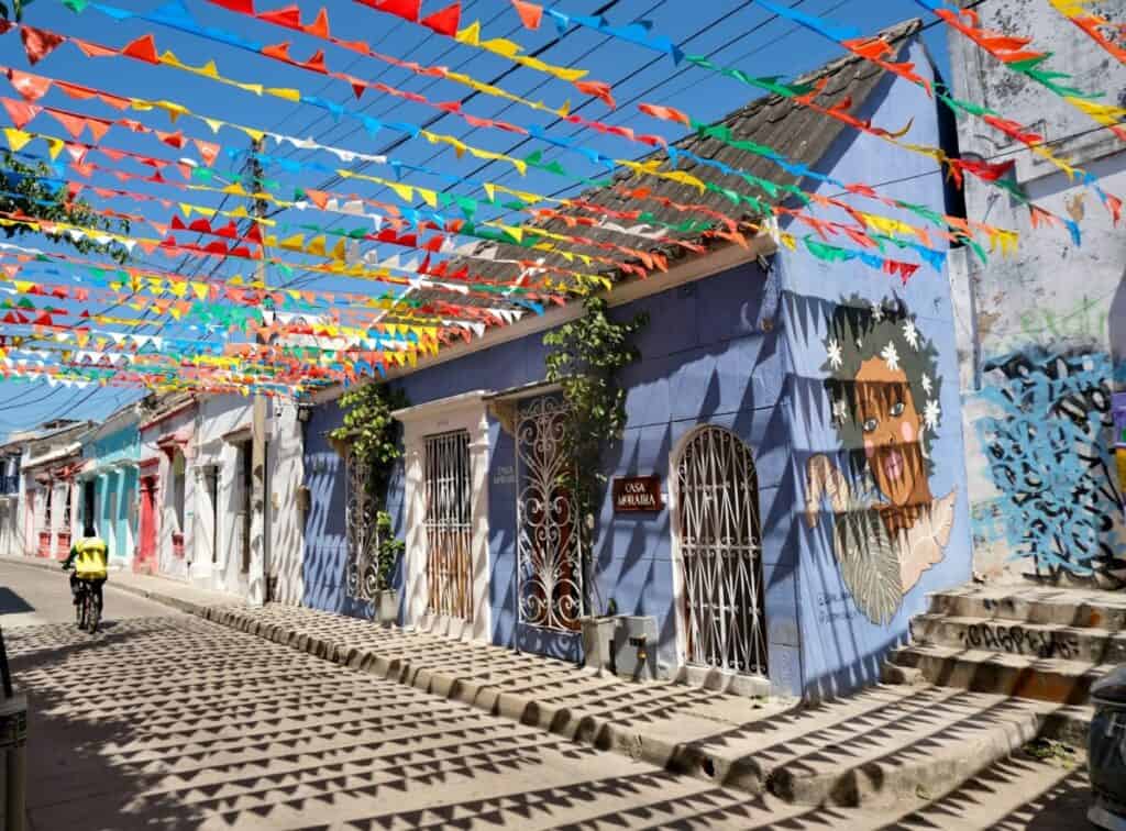 Getsemaní Cartagena Colombia | a man riding a bike down a street next to a blue building